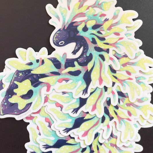 A photo of several matte vinyl stickers depicting a fictional aquatic salamander painting. The salamander is purple with stars on its body and is entangled in colorful kelp. This listing is for a single sticker, even though more are shown in this photo.