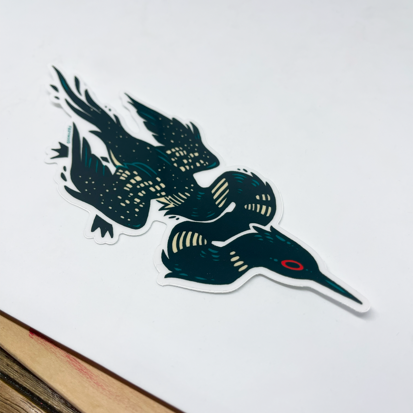A transparent vinyl sticker of an illustrated Loon with an extra long and twisty neck.