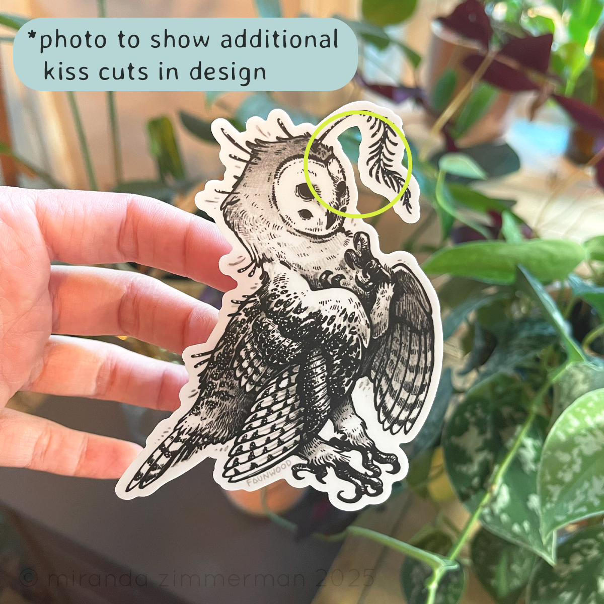 Hand holding a vinyl sticker depicting a black and white owl-creature. 