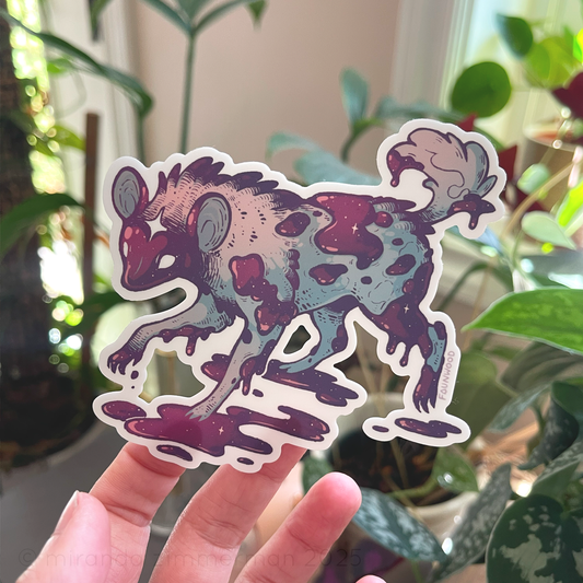 A die cut matte vinyl sticker featuring an illustration of an African wild dog with purple and pink coloration.  The sticker is being held up by a hand, showing the additional kiss cut elements.